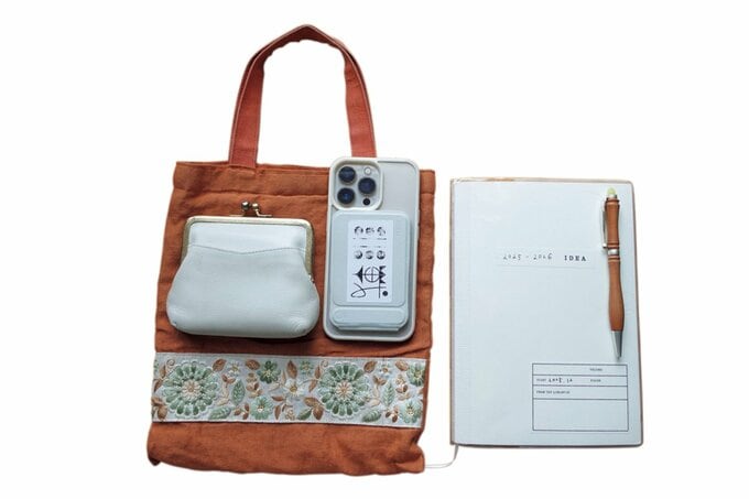 並べられたカバンとスマホと財布とノートとペンの写真