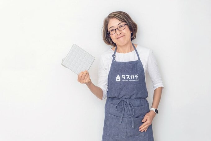 排水溝のフタを持ってほほ笑む女性