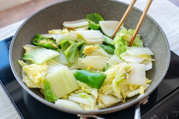 （2）フライパンにごま油（大さじ1/2）を中火で熱し、白菜とピーマンをさっと炒めて油が 回ったら一度取り出す。