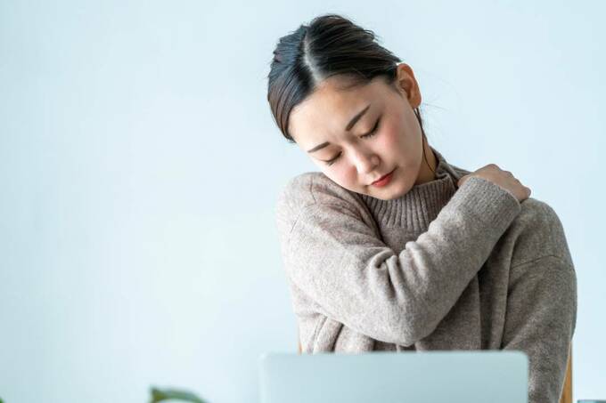 肩をさわる女性