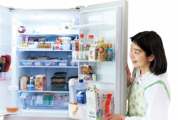 食品が詰まった冷蔵庫を開けて横からのぞき込む女性