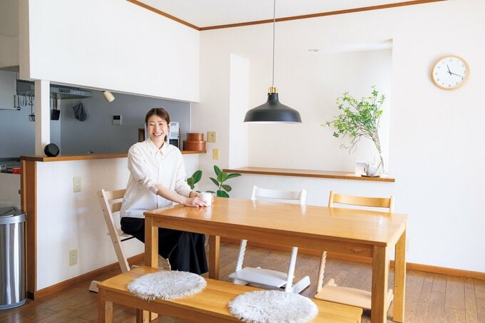 ダイニングキッチンで椅子に座りこちらを向いて微笑む女性