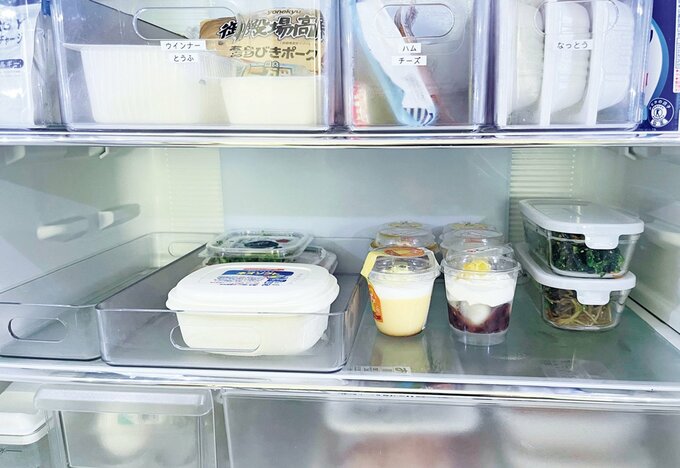 冷蔵庫内でラベルが貼られた透明のボックスに入った状態で並ぶ食品とプリンなどのデザート