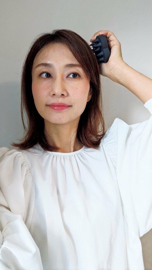 スカルプブラシを頭にあてる女性