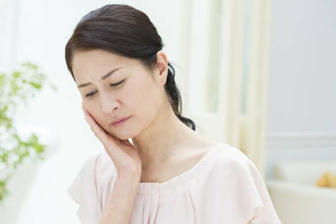 頬をおさえる女性