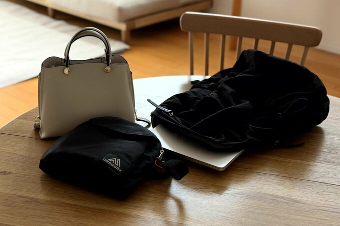 机の上にバッグが3つある。ノートパソコンの入った黒いリュック。ベージュのミニバッグ。黒いショルダーバッグ