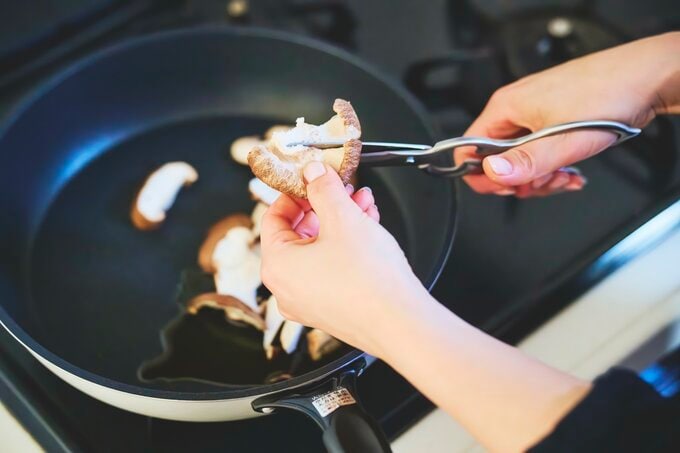 フライパンの上でシイタケをキッチンバサミで切る図