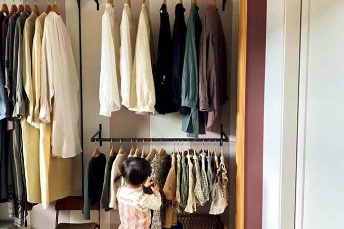 おしゃれなオープンクローゼットで洋服を選ぶ2歳の女の子