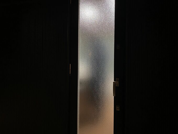 すりガラスの勝手口の前に人が立っているところ