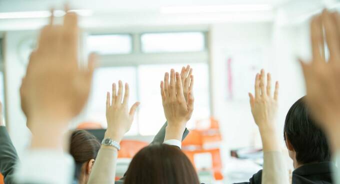 大勢の人たちが挙手する様子
