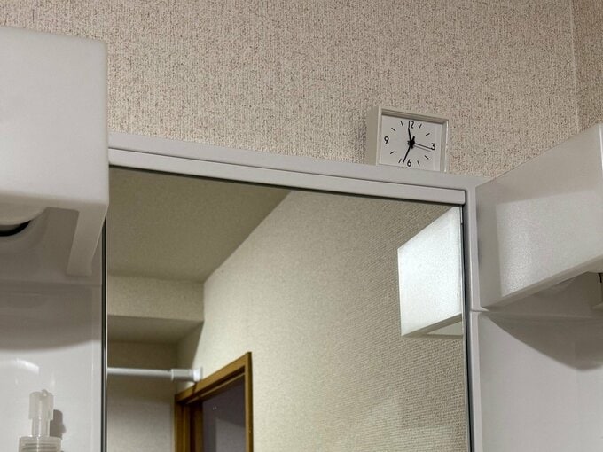 洗面所の鏡の上にミニ時計を置く