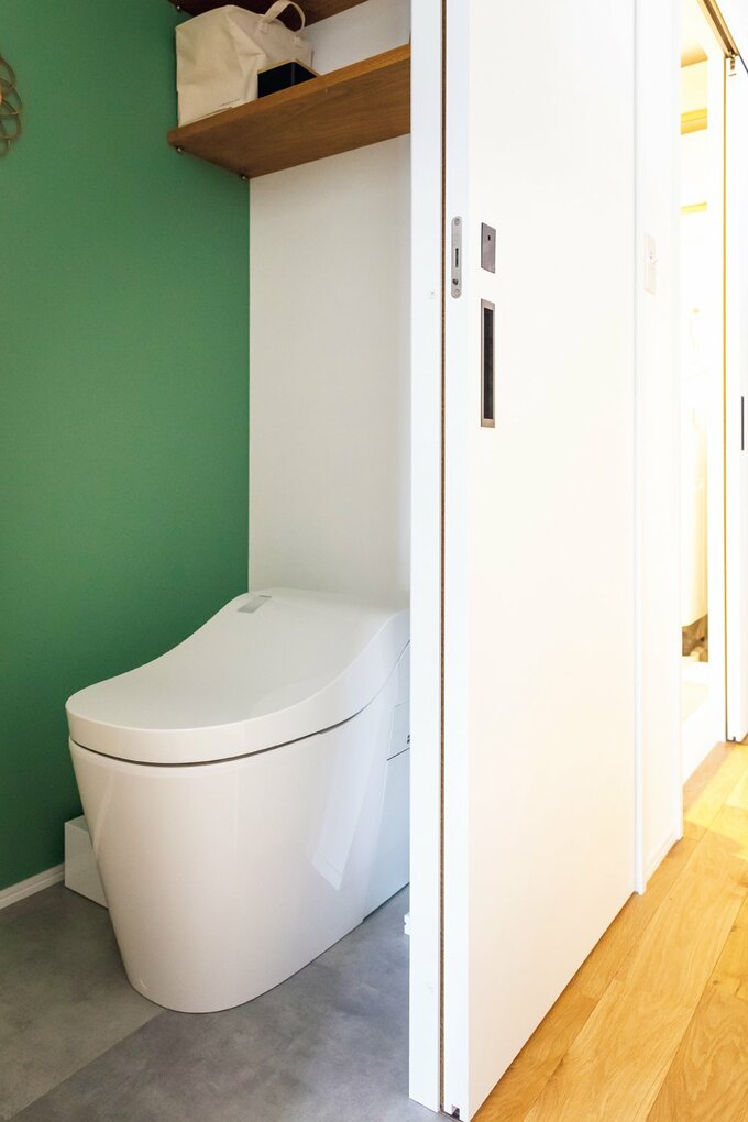 壁をフォレストグリーンのクロスで北欧風に仕上げたトイレ