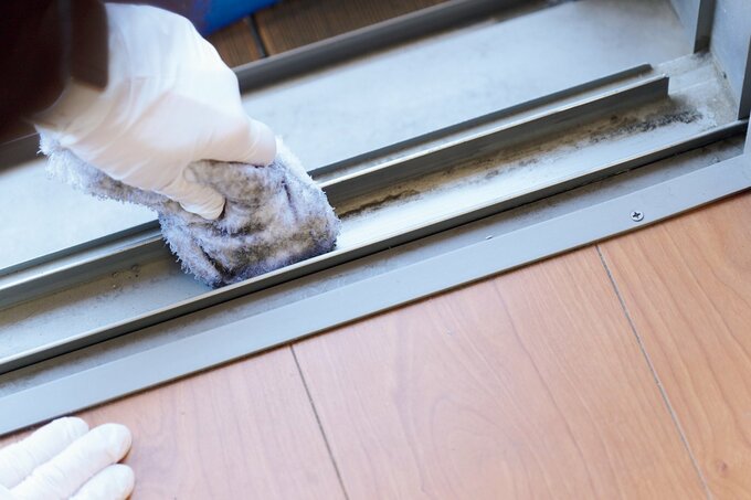 窓のレールを掃除するハウスキーパー