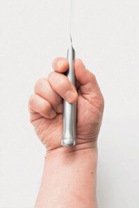 親指と人さし指で包丁の柄のつけ根を持つ