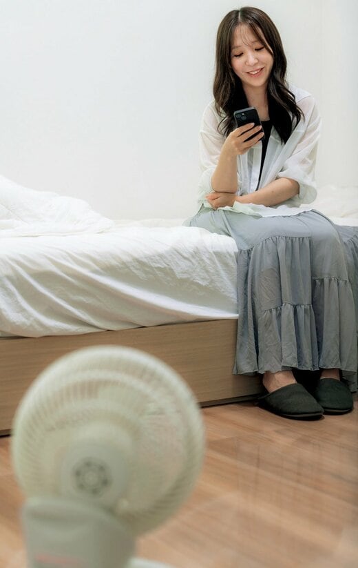 ベッドに座る女性とサーキュレーター