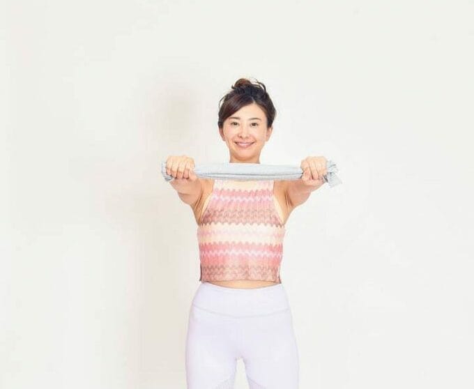 タオルを両手で引っ張るように持つ女性