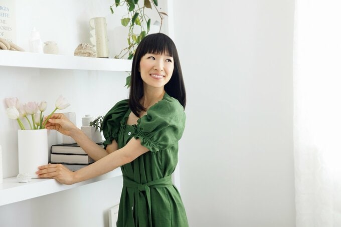 緑のワンピースを着た女性が棚の前に立って振り向く様子