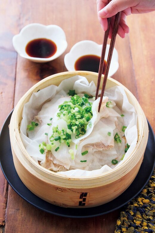 せいろに入った大根と豚しゃぶの重ね蒸しを箸でつまんでいる