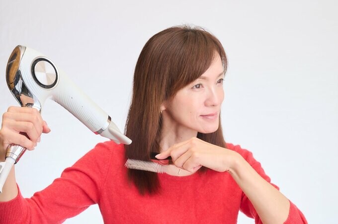 ドライヤーでブローをする女性