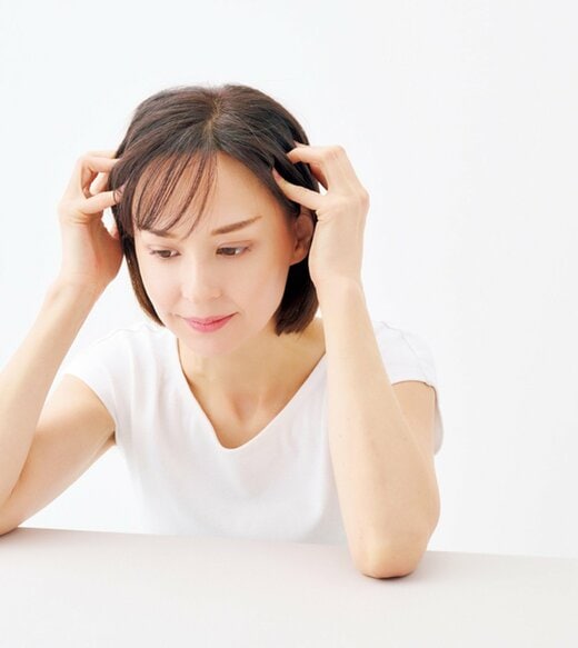 こめかみの辺りを指で押し上げる女性