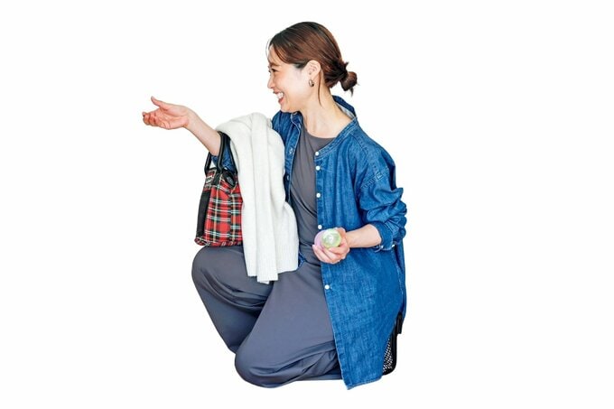 笑顔でカプセルトイを回しているデニムシャツの女性