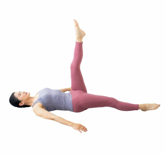 仰向けになって片足を上げ片足を伸ばしている女性