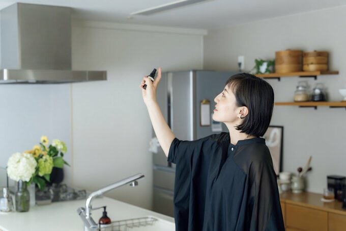女性がキッチンでルームスプレーを吹きかける様子