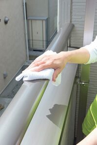 手すりやエアコン室外機をぞうきんで水ぶきする