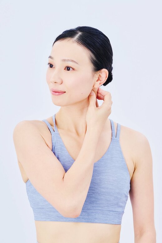 右手で左の胸鎖乳突筋をつかむ女性