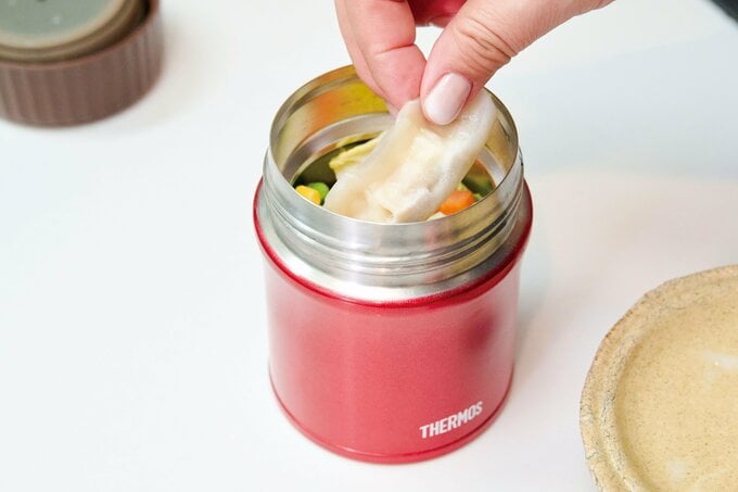 スープジャーに野菜と餃子を入れている