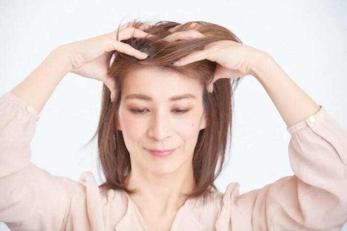 両手で髪をもむ女性