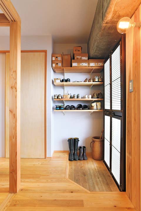オープンな下駄箱のある、木材を多用した玄関