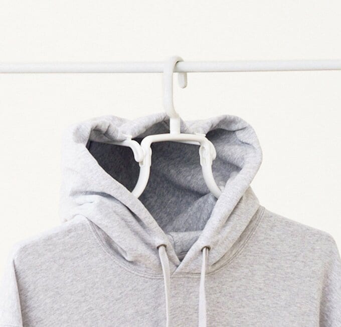 フードを引っかけるところがついているハンガーにかかったグレーのパーカー