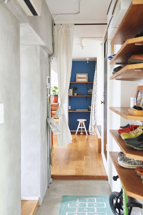 ブルーの壁紙のパソコンコーナーが正面に見える玄関