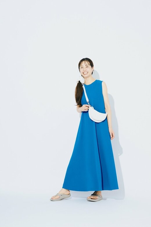 ブルーのAラインワンピとホワイトのバッグを身に着けた女性