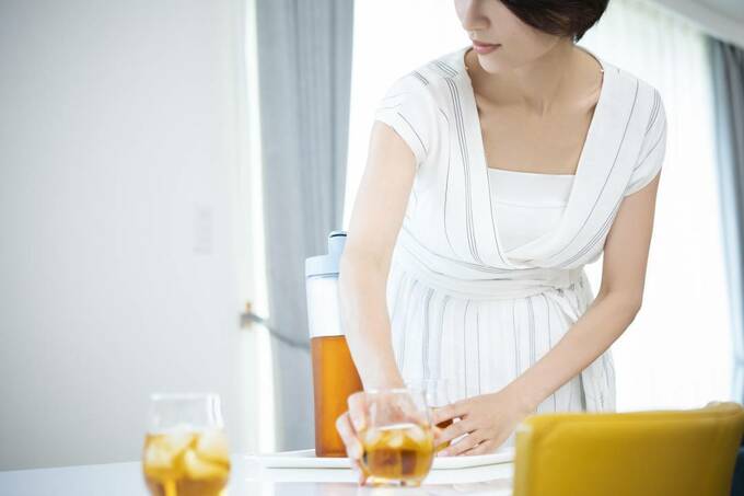 机に飲み物が入ったコップを置く女性