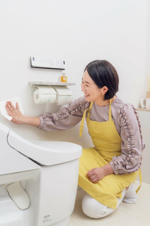 トイレ用掃除シートで壁をふく女性