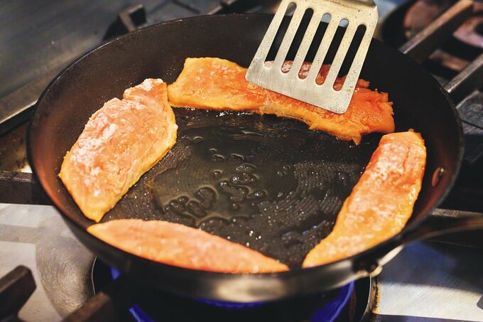 フライパンのフチで魚の皮目を焼く様子