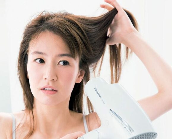 下から上へドライヤーをかける女性