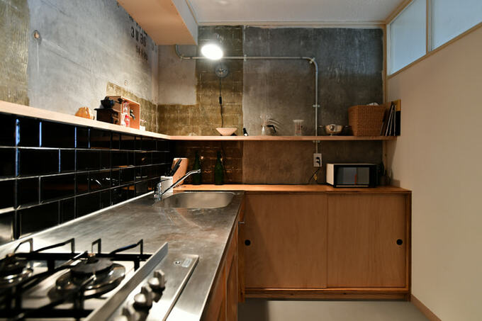 壁の一部を現しにして黒タイルで仕上げたキッチン