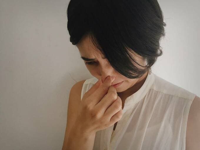 女性が鼻をつまんでいる様子