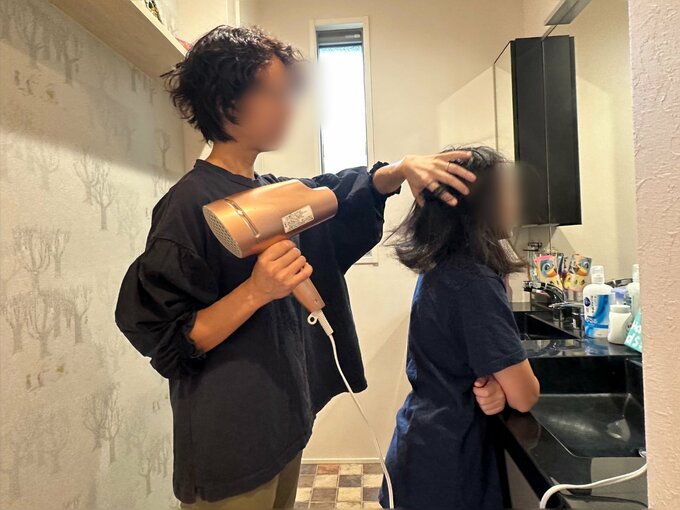 洗面所でドライヤーをする親子