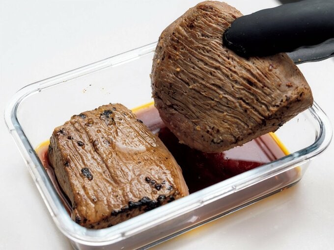 さっと焼いた牛モモかたまり肉をタレにつけているところ