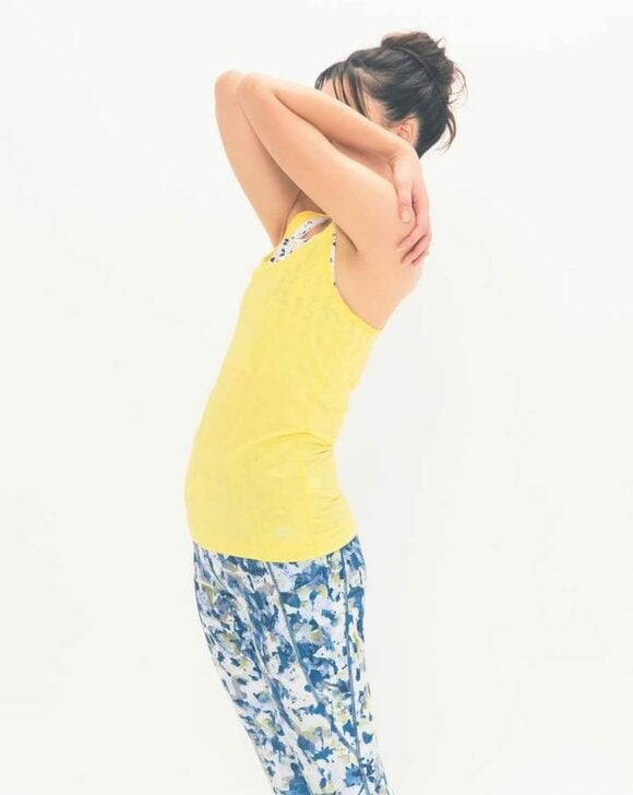 黄色の服を着た女性ひじつけて上にあげる