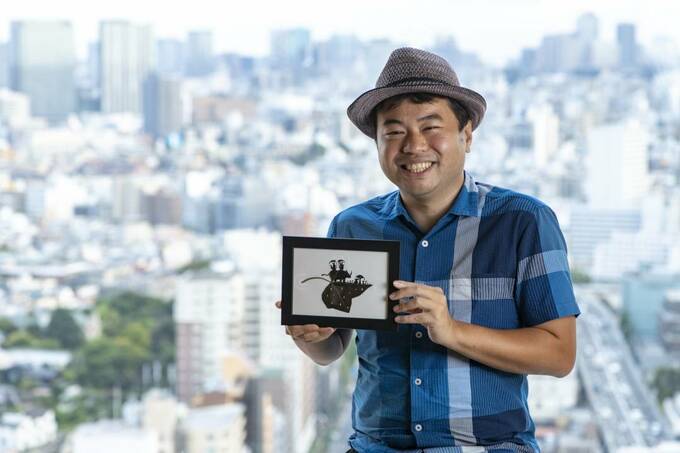 絵を持って微笑む男性