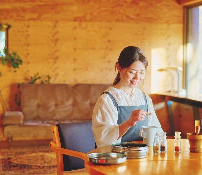 ハーブを調合するエプロン姿の女性