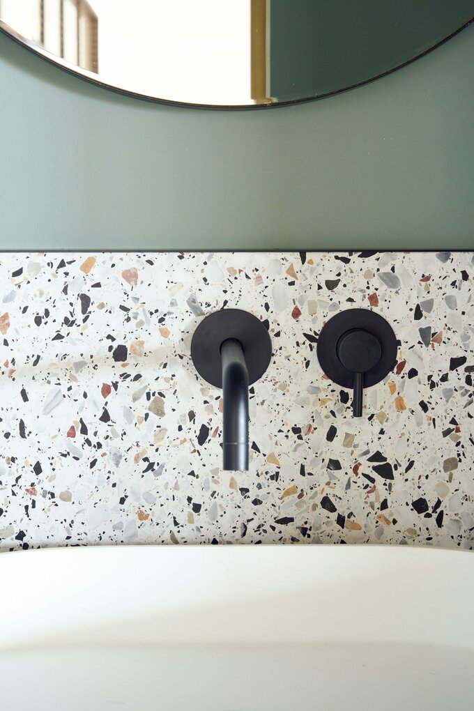 グレイッシュなグリーンの壁に合わせたテラゾータイル