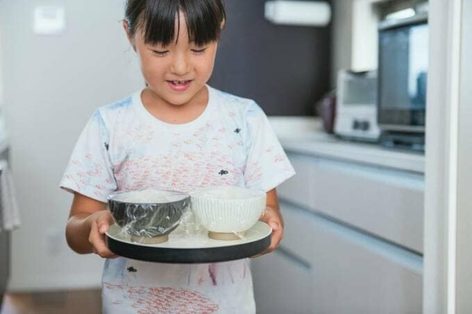 子どもが丸盆でご飯を運ぶ様子