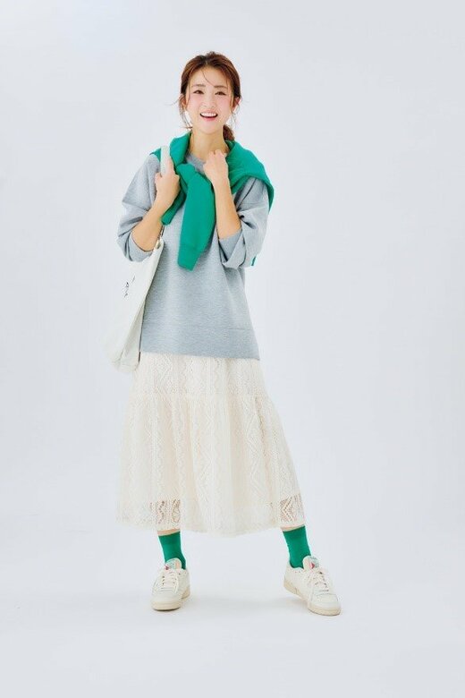 カバンを肩にかけて笑顔で立つ女性