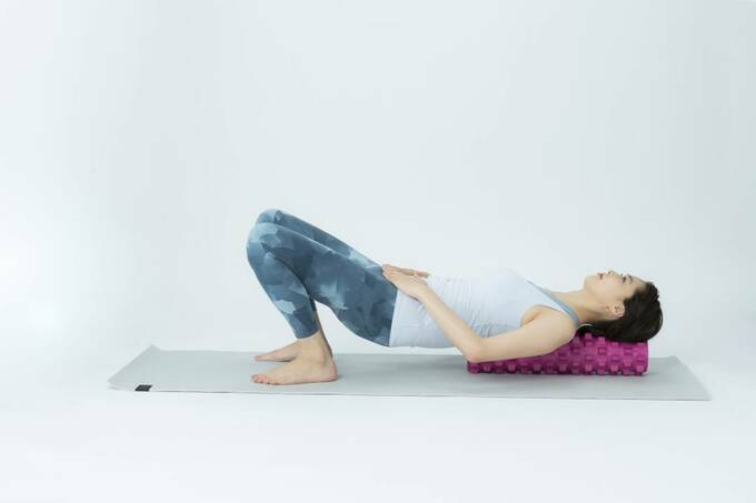 ひざを曲げ、指先で三角形をつくって恥骨に置き、お尻を浮かす